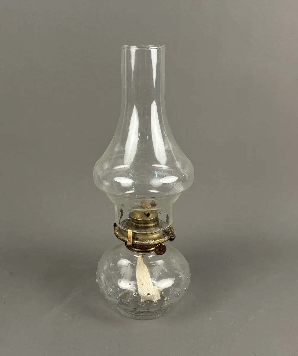 Antike Petroleumlampe aus klarem Glas mit einem Messingbrenner.